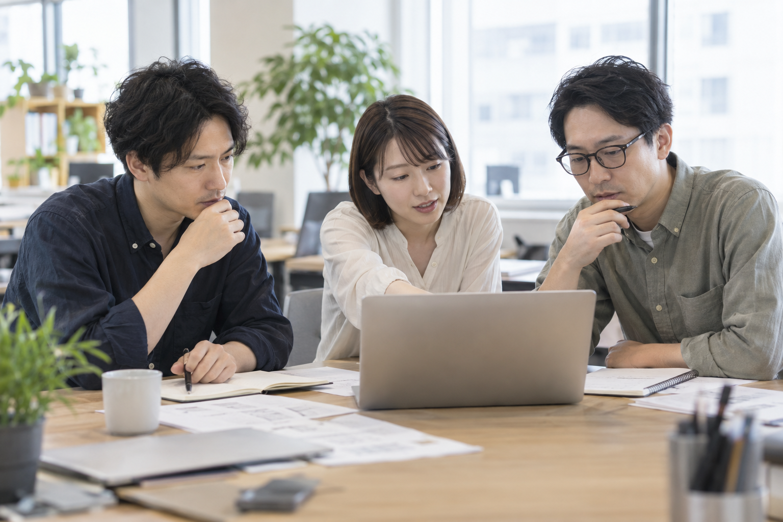 ノートパソコンと資料を見ながら、システムの引き継ぎ内容を確認するエンジニアたちのイメージ写真